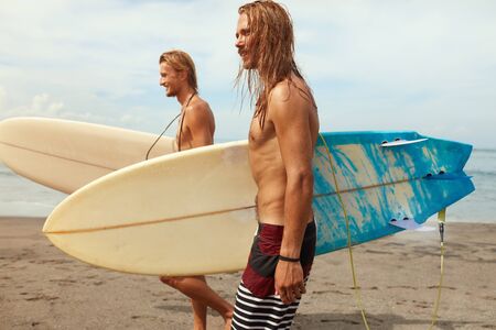 Surfing. Handsome Surfers With Surfboards. Young Men Walking On Ocean Beach. Active Lifestyle, Water Sport On Beautiful Sea Background.の写真素材