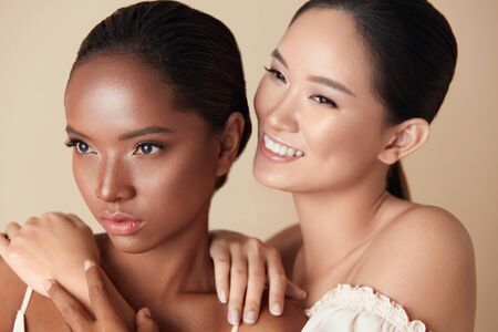 Diversity. Beauty Women Portrait. Mixed Race And Asian Models Hugs Each Other And Looking Away. Multi-Ethnic Female With Natural Makeup And Different Skin Types On Beige Background.の写真素材