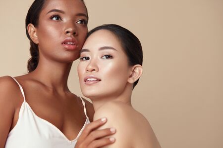 Beauty. Diverse Models Portrait With Copy Space For Advertising. Tender Asian And Mixed Race Women Posing Together On Beige Background. Female With Perfect Skin And Natural Makeup.の写真素材