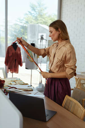 Woman. Fashion Designer Working At Workshop. Professional Tailor Measuring Fabric For Dress. Self Employed Female Creates Stylish Clothes At Own Clothing Atelier. From Startup To Successful Business.の写真素材