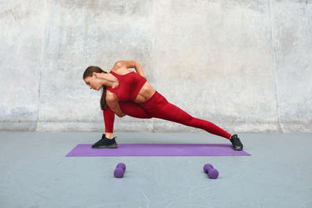 Fitness Girl Doing Twisting Exercise On Yoga Mat At Outdoor Stadium. Fit Woman With Strong Muscular Body.の写真素材