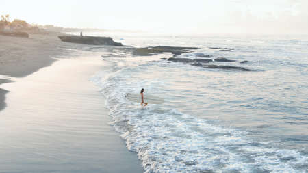 Surfer. Surfing Girl With Surfboard Going To Surf In Ocean. Water Sport As Part Of Active Lifestyle. Surfboarding On Summer Vacation At Tropical Sea.の写真素材