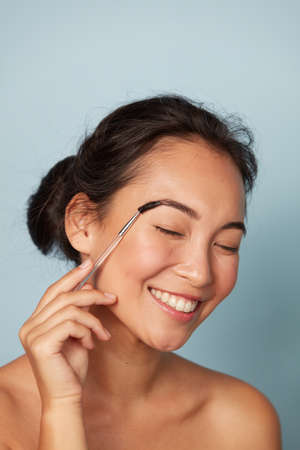 Beauty. Woman brushing eyebrows with makeup brush portraitの写真素材