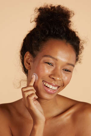 Face skin care. Woman applying cosmetic cream on skin portraitの写真素材