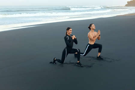 Beach. Sport Couple Stretching On Coast. Man And Woman With Perfect Body In Fashion Sportswear Warming Up Before Intense Workout Outdoor. Training On Resort At Sunrise As Part Of Active Lifestyle.の写真素材