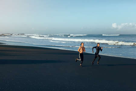 Sport On Beach. Running Couple In Fashion Sportswear On Morning Workout. Sexy Man And Beautiful Woman Jogging Along Ocean Coastline. Active Lifestyle On Summer Vacation At Tropical Sea.の写真素材
