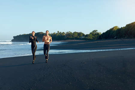 Beach. Sport Couple Running During Morning Workout. Handsome Shirtless Man And Sexy Woman In Fashion Sporty Outfit Training On Coast. Active Summer Vacation At Tropical Ocean As Lifestyle.の写真素材