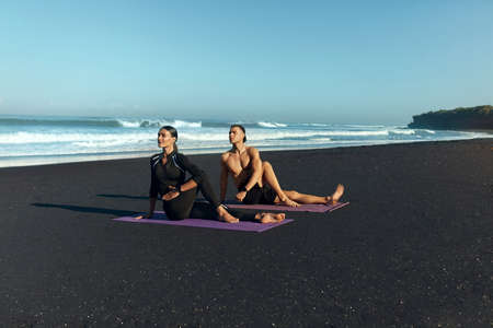 Couple Workout On Beach. Male And Female Doing Twist Exercise On Yoga Mat In Morning. Handsome Man And Sexy Woman In Fashion Sporty Outfit Stretching. Active Summer Vacation At Tropical Sea.の写真素材