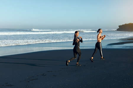Fitness. Running On Beach As Lifestyle. Sport Couple In Fashion Sporty Outfit Working Out On Coast. Sexy Man And Beautiful Woman Training Outdoor. Active Summer Vacation At Tropical Sea.の写真素材