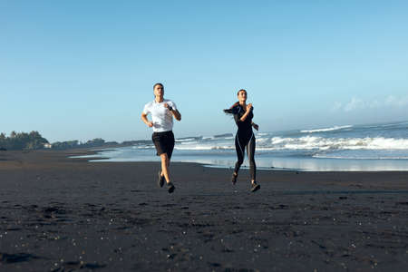Beach. Sport Couple Running During Morning Workout. Handsome Man And Sexy Woman In Fashion Sporty Outfit Training On Coast. Active Summer Vacation At Tropical Ocean As Lifestyle.の写真素材