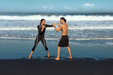 Beach. Couple Boxing Full-Length Portrait. Shirtless Man Training Sexy Woman To Punch. Partner Workout On Summer Vacation As Part Of Active Lifestyle. Male And Female In Fashion Sporty Outfit.の写真素材