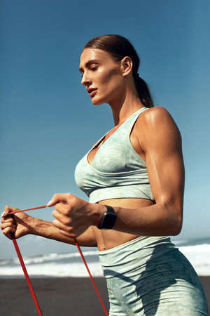 Beach. Fitness Girl Stretching With Resistance Band Outdoor. Sexy Woman In Fashion Sporty Outfit Doing Flexibility Exercise With Rubber Loop. Active Lifestyle On Summer Vacation.の写真素材