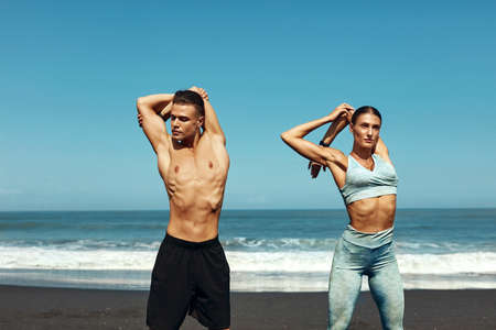 Sport On Beach. Stretching Couple In Fashion Sportswear Workout. Sexy Man And Beautiful Woman Warming Up Before Exercising. Active Lifestyle On Summer Vacation At Tropical Sea.の写真素材