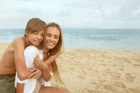 Summer. Family Picnic On Beach. Portrait Of Young Woman With Son Enjoying Lunch At Tropical Ocean. Mother And Handsome Boy On Vacation Near Sea. Organic Fruit And Natural Vitamins.の写真素材