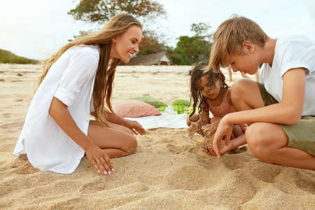 Summer. Family Picnic On Beach. Portrait Of Young Woman With Son Enjoying Lunch At Tropical Ocean. Mother And Handsome Boy On Vacation Near Sea. Organic Fruit And Natural Vitamins.の写真素材