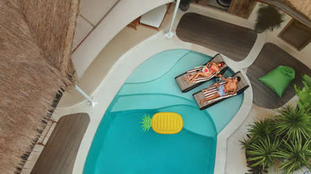 Man And Woman At Pool. Top View Of Couple In Love Enjoying Summer Vacation In Villa. Handsome Guy And Beautiful Girl Eating Fruit And Chilling On Poolside. Leisure On Sun Chair During Honeymoon.の写真素材