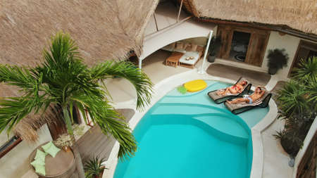 Summer. Top View Of Couple In Love At Pool. Happy Man And Woman Enjoying Honeymoon At Tropical Villa With Straw Roof. Fashion Male And Female On Romantic Vacation At Luxury Cottage.の写真素材