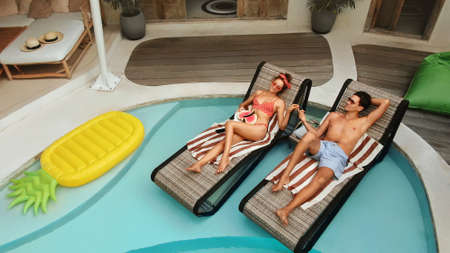 Man And Woman At Pool. Top View Of Couple In Love Enjoying Summer Vacation At Tropical Villa. Handsome Guy And Beautiful Girl Chilling On Poolside. Honeymoon At Luxury Cottage.の写真素材