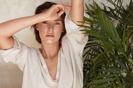 Beauty. Portrait Of Woman Against Tropical Greenery. Beautiful Model Posing Near Palm Leaves And Looking At Camera. Tender Brunette With Natural Makeup, Radiant And Glowing Facial Skin.の写真素材