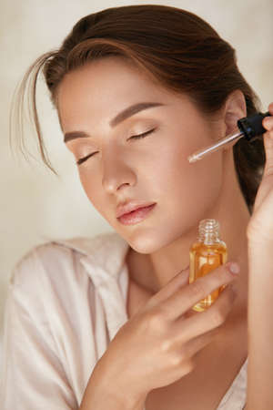 Skin Care. Woman Applying Essential Oil With Dropper On Face. Natural Cosmetic Product For Hydrated, Glowing And Healthy Facial Derma. Portrait Of Beauty Model With Perfect Skin.の写真素材