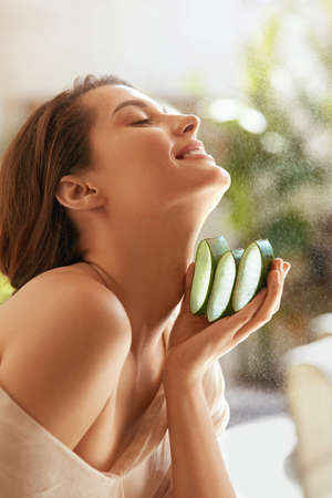 Woman With Aloe Vera. Happy Model Holding Fresh Juicy Slices Of Leaf. Organic Cosmetic For Hydrated Skin. Young Tender Brunette With Naked Shoulder Posing With Closed Eyes.の写真素材