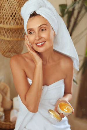 Beauty Mask. Woman In Bath Towel Applying Skin Care Product. Morning Routine As Part Of Anti-Aging Therapy. Happy Naked Shoulders Model After Shower Looking Aside.の写真素材