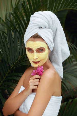 Skin Care. Woman With Yellow Clay Mask On Face. Female In Bath Towel After Applying Beauty Product With Turmeric. SPA Treatment And Anti-Aging Therapy For Perfect Facial Derma.の写真素材