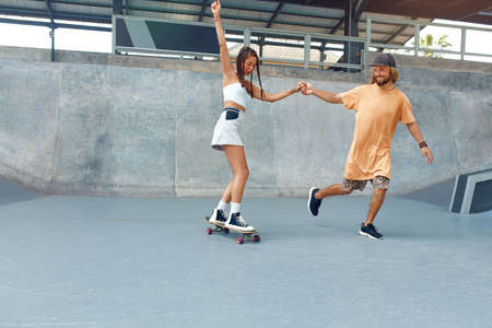 Skateboarding. Couple In Casual Outfit Riding On Skateboard At Skatepark. Skater Subculture And Summer Activity As Lifestyle. Extreme Sport For Active Urban Guys And Girls.の写真素材