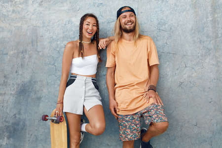 Couple With Skateboards Portrait. Happy Guy And Girl In Casual Outfit Against Concrete Wall At Skatepark. Urban Subculture And Skateboarding As Lifestyle Of Active People In City.の写真素材