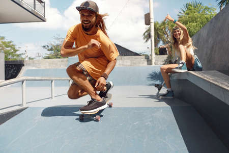 Summer. Skater Friends Skateboarding At Skatepark. Guy And Girl In Casual Outfit Having Fun Outdoor. Happy Couple Training With Skateboards On Concrete Ramp. Extreme Sport As Urban Lifestyle.の写真素材