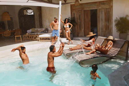 Water Recreation In Pool. Boys Splashing Aqua And Having Fun With Their Girlfriends On Family Weekend. Group Of Happy People Enjoying Leisure At Tropical Resort.の写真素材