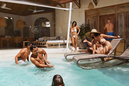 Family Fun In Pool. Group Of Happy People Splashing Water And Enjoying Leisure On Weekend. Summer Activity At Tropical Resort. Vacation Entertainment As Lifestyle.の写真素材