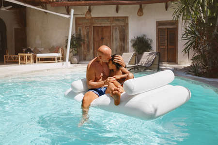 Family At Pool. Father Hugging And Comforting Son. Dad With Little Boy Sunbathing And Floating On Inflatable Water Mattress. Parent And Kid Enjoying Vacation At Tropical Resort.の写真素材