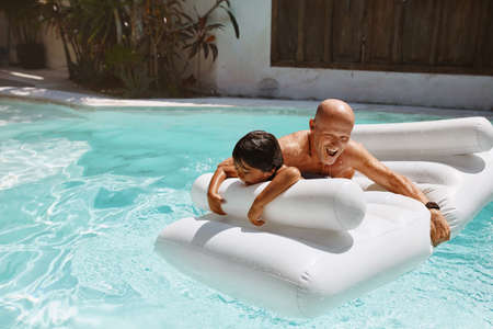 Summer Activity. Pool Entertainment With Kid On Vacation At Tropical Resort. Father With Son Floating On Inflatable Water Mattress In Hot Weather. Fun Family Weekend As Lifestyle.の写真素材