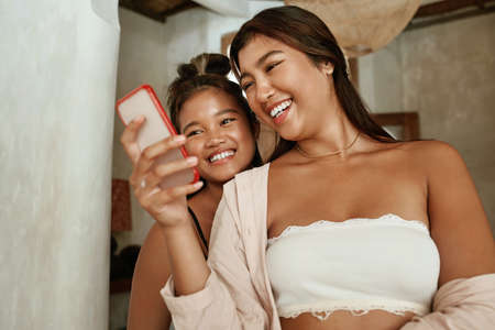 Girls Doing Selfie. Friends Using Smartphone For Taking Photo. Young Women Looking At Digital Device Screen And Smiling. Summer Fun On Family Weekend Or Vacation At Tropical Villa.の写真素材
