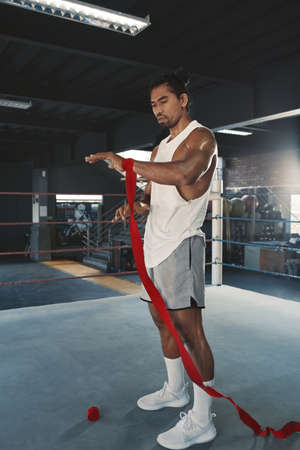 Man With Hand Wrap On Boxing Ring. Portrait Of Sportsman With Muscular Body Using Wrist Bandage For Training At Gym. Portrait Of Handsome Asian Guy On Workout.の写真素材