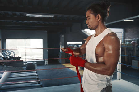 Gym. Man Wrapping Hand Bandage Before Workout On Boxing Ring. Asian Sportsman Training At Fitness Center. Portrait Of Sexy Handsome Guy With Strong, Healthy, Muscular Body.の写真素材