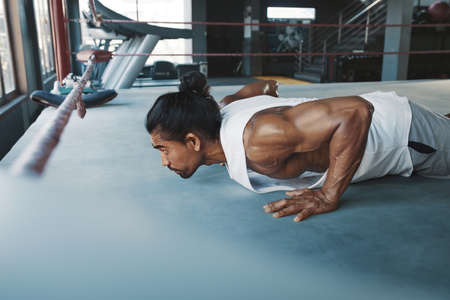 Workout. Man Doing Push-Ups On Boxing Ring. Asian Sportsman Exercising For Strong, Healthy, Muscular Body. Sexy Guy Training At Fitness Center.の写真素材
