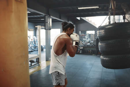 Workout. Man Boxing Tire Bag. Sexy Sportsman In Gloves Punching Heavy Equipment At Gym. Portrait Of Sexy Guy With Strong, Healthy, Muscular Body Training At Fitness Center.の写真素材