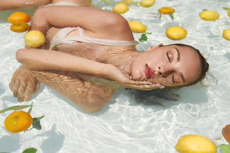 Beautiful Womans Portrait In Pool With Citrus. Model In Bikini Enjoying Sunny Day At SPA.の写真素材