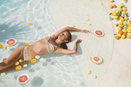 SPA Model In Pool With Citrus. Beautiful Girl In Bikini Floating With Fresh Tropical Fruit At Resort.の写真素材