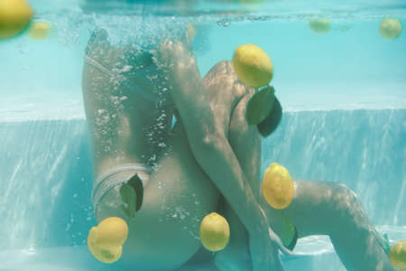 Womans Body Underwater. Sexy Model In Bikini Floating In Pool With Fresh Citrus At SPA.の写真素材
