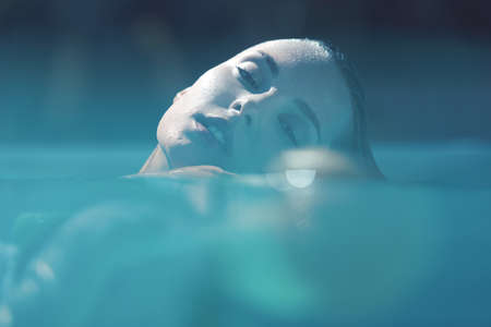 Beautiful Girl Portrait At SPA. Young Woman Relaxing In Pool.の写真素材