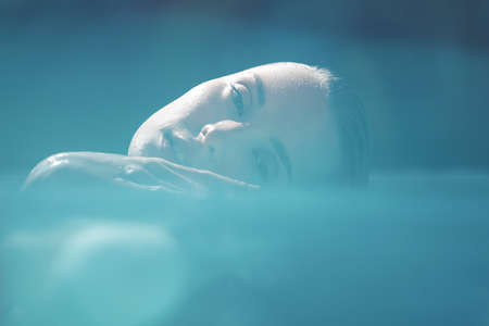 Beautiful Girl Face Portrait. Woman Floating In Pool And Enjoying Recreation At SPA.の写真素材