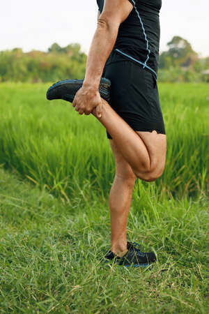 Caucasian Manâs Stretching Before Running Close Up Portrait. Sportive Male Warming Up Before Jogging Workout On Paddy Field.の写真素材
