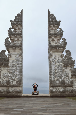 Beautiful Girl In Lotus Position Meditating In Pura Lempuyang Temple In Bali, Indonesia.の写真素材