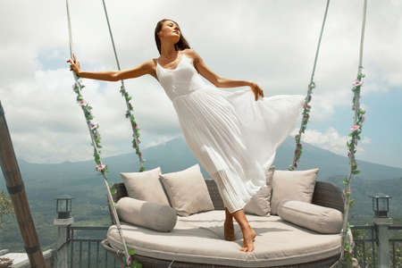 Beautiful Girl Standing On Sky Swing Portrait In Bali, Indonesia.の写真素材