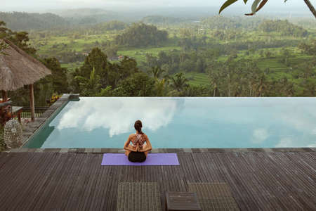 Beautiful Girl Doing Yoga On Poolside In Morning In Bali, Indonesia.の写真素材
