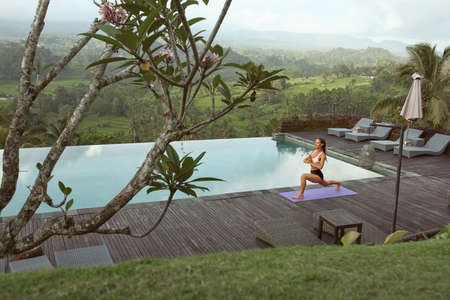 Beautiful Girl Doing Yoga On Poolside In Morning In Bali, Indonesia.の写真素材