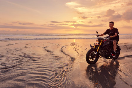 Man And Motorcycle On Ocean Beach At Beautiful Tropical Sunset. Handsome Biker On Motorbike On Sandy...